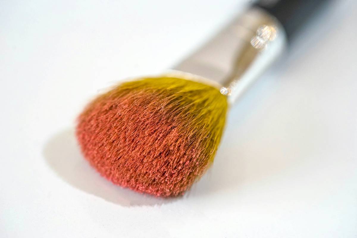 powder applicator held near cheekbone showing soft, velvety dome for seamless blending