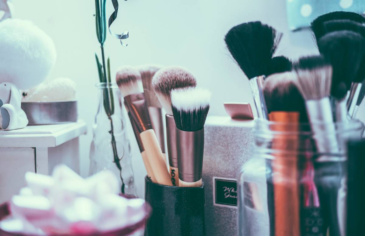 Close-up of a makeup foundation brush blending liquid foundation into skin for seamless coverage
